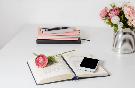 cahier blanc sur une table avec un bouquet de fleur dans le fond