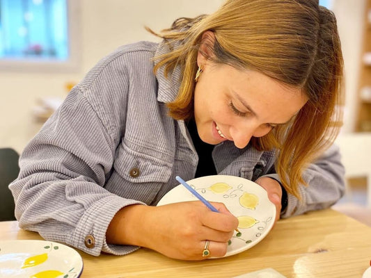 Femme qui dessine sur une assiette céramique dans un atelier offert pour la fête des mères